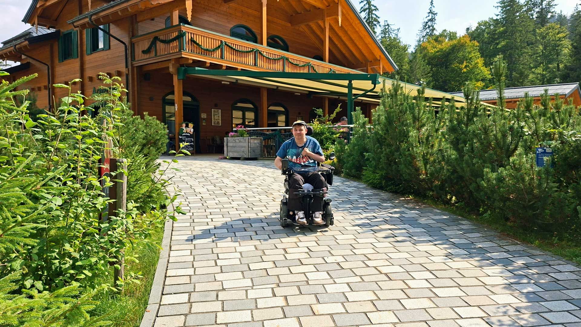 Helmut im E-Rolli auf dem Weg vor der Restaurant-Terrasse