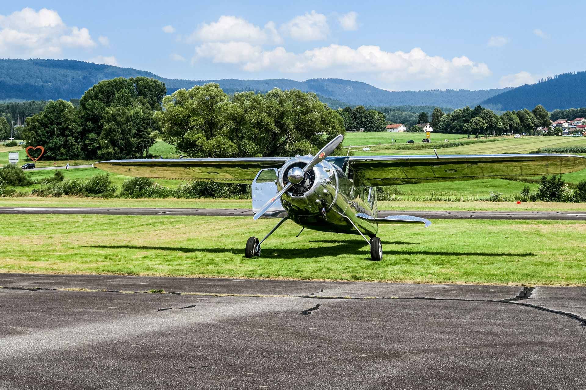 silberfarbenes Propellerflugzeug neben dem Rollfeld